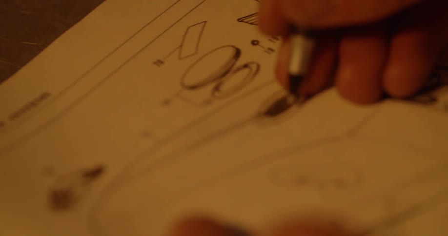 A man is tracing a line on a diagram in a book