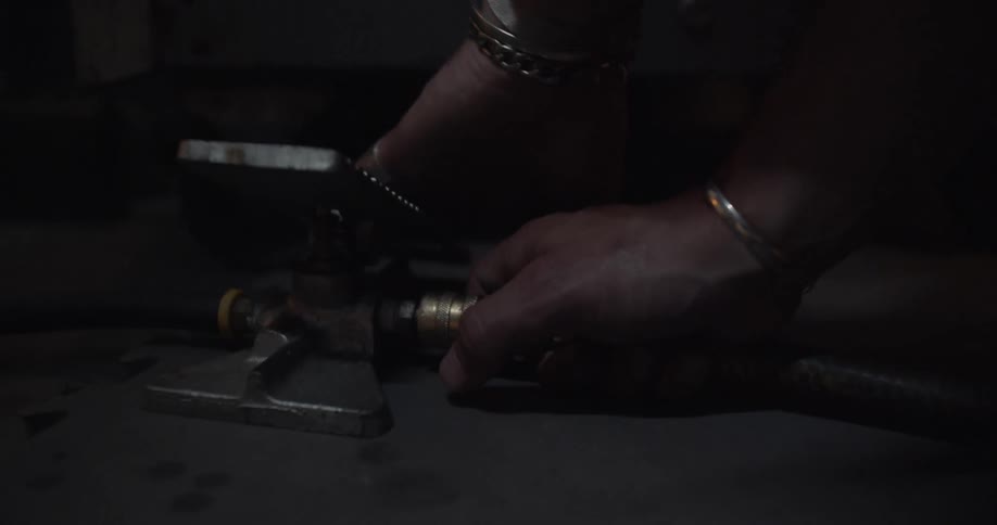A man is pressing a pedal with his hand and adjusting a hose