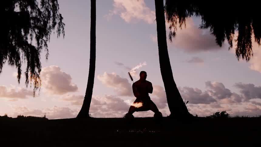 Fire dancer performing at sunset on the beach