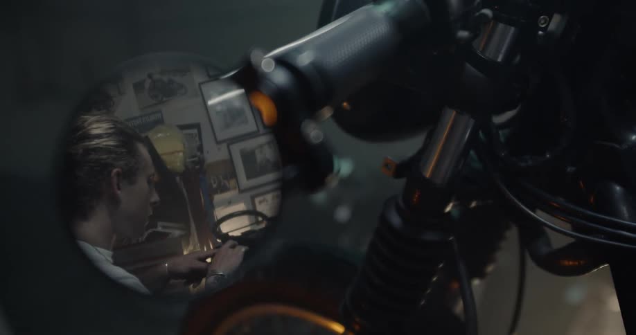 A man is working on a motorcycle inside a garage at night