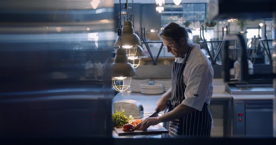 Man is chopping vegetables in restaurant kitchen