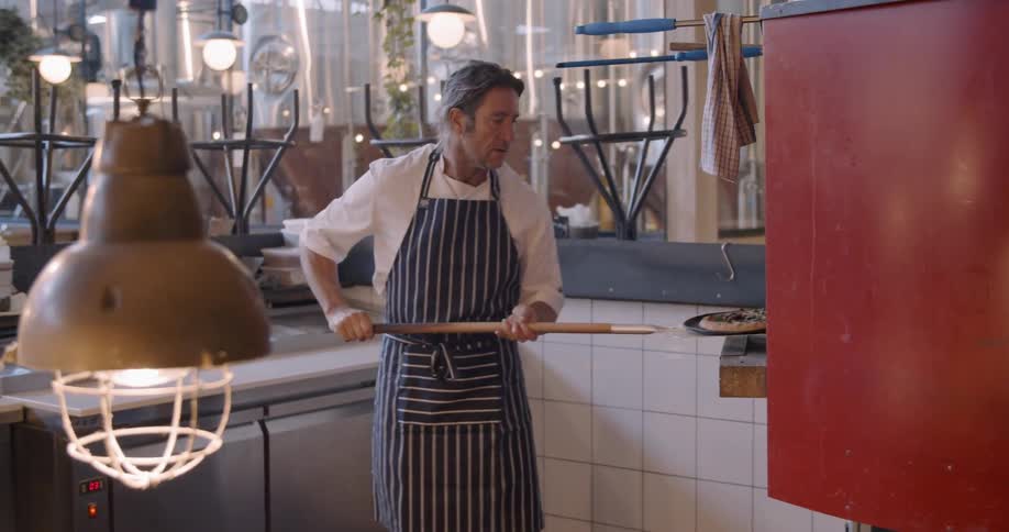 A chef makes pizza in a restaurant kitchen