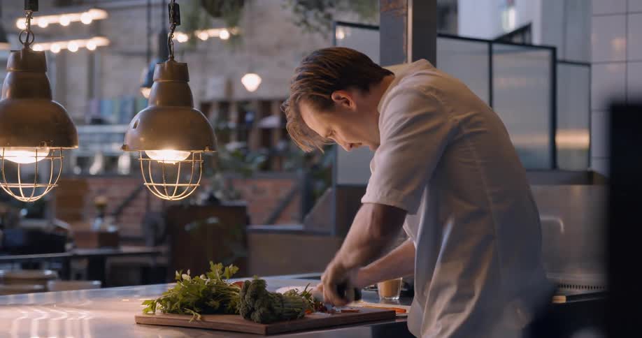 A chef cuts vegetables in a restaurant kitchen