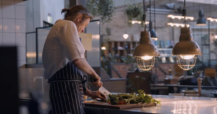 A chef cuts vegetables in a restaurant kitchen
