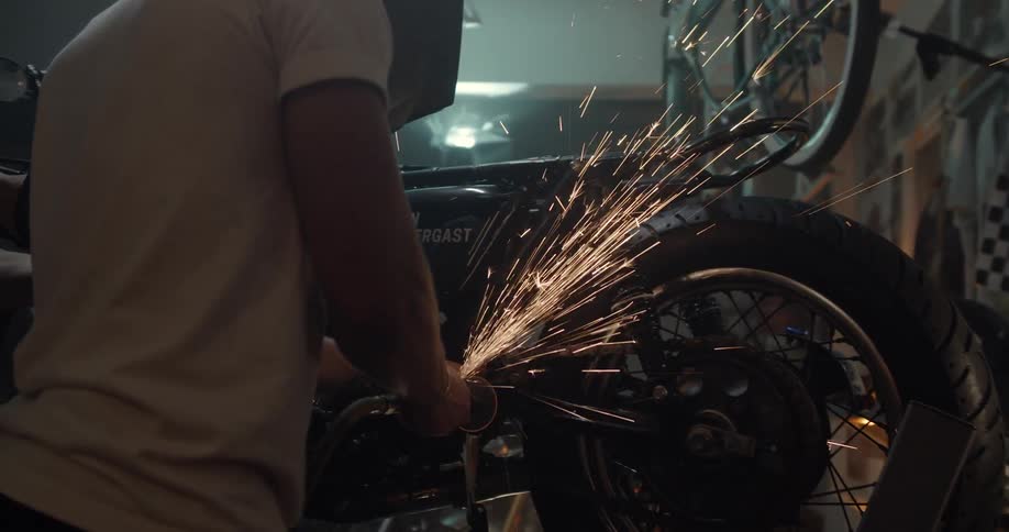 A man works with a grinder on a motorcycle