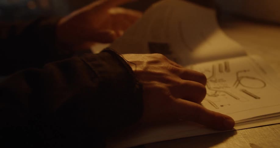 A person looks at an instruction manual at a workbench