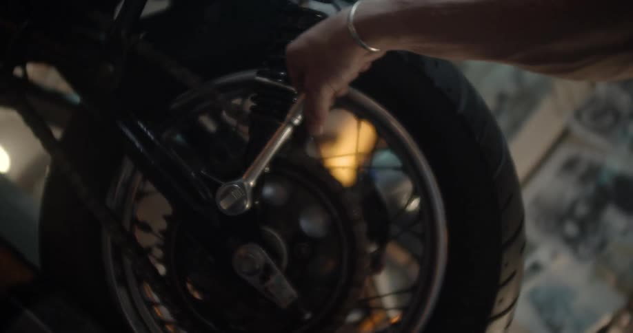 A man uses a tool on a motorcycle tire