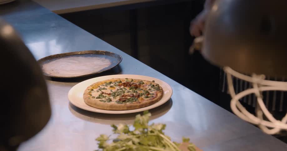 A chef makes pizza in a restaurant kitchen