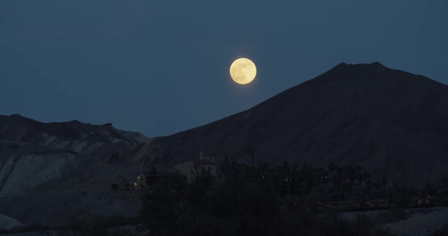 Hazy full moon rises over a mountain