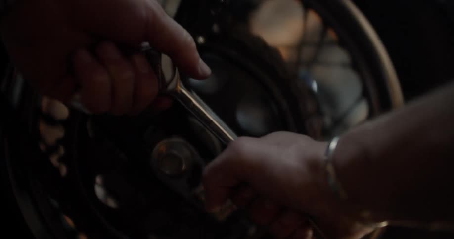 A man uses a tool on a motorcycle tire