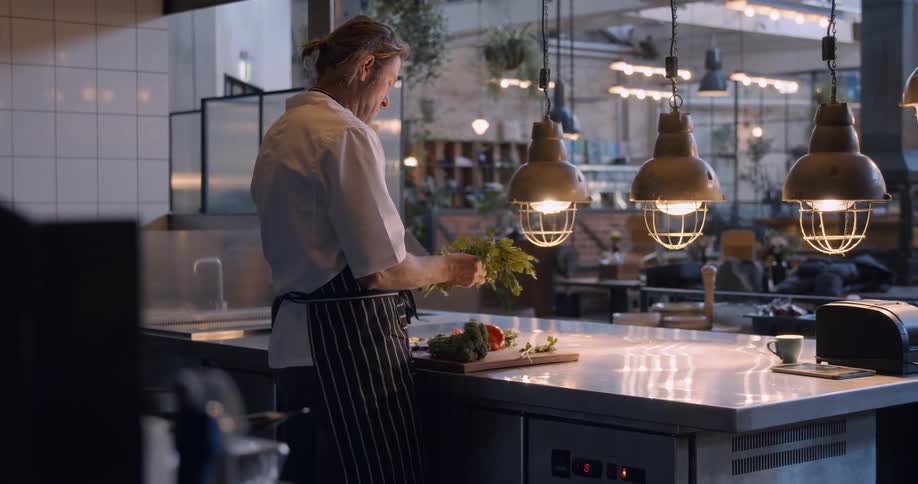 A chef cuts vegetables in a restaurant kitchen