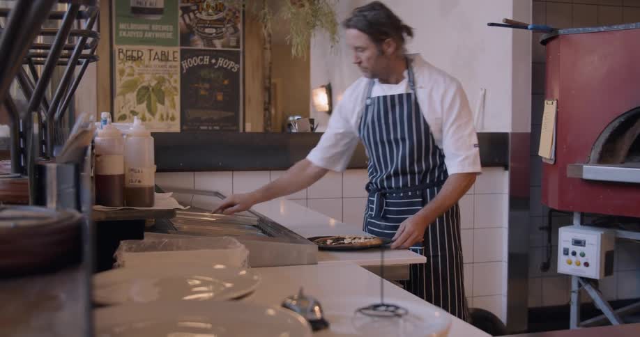 A chef makes pizza in a restaurant kitchen