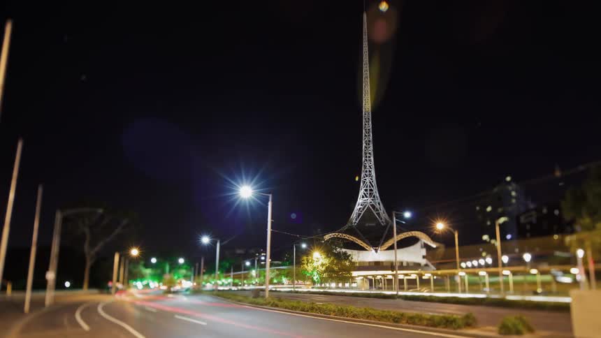 Lights from traffic and a tower flash and blur at night