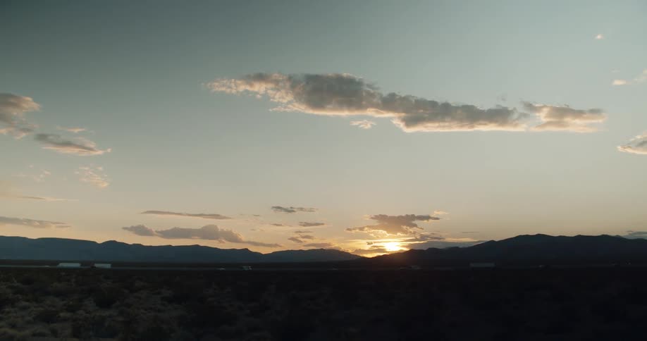The sun sets over highway and mountains