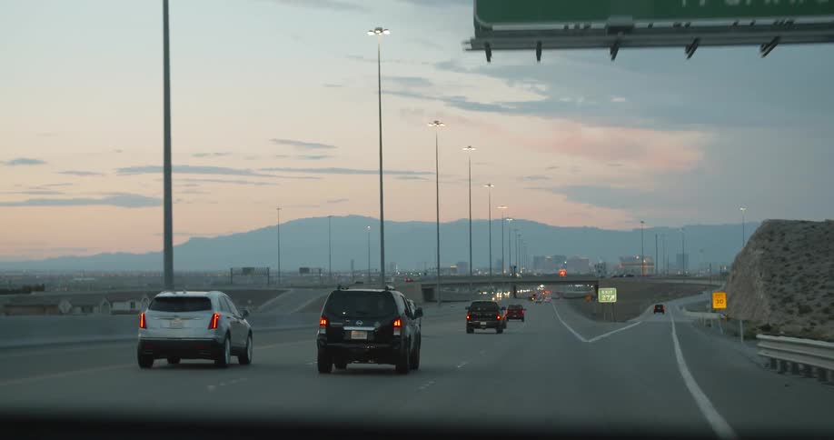 Cars travel down highway at sunset