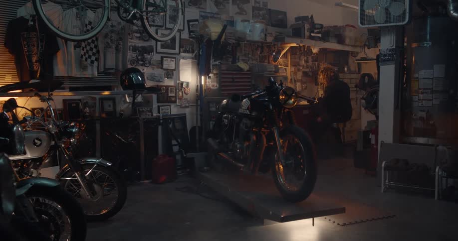 A man is sitting at a bench in the garage