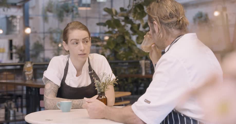 Two chefs talk at a table