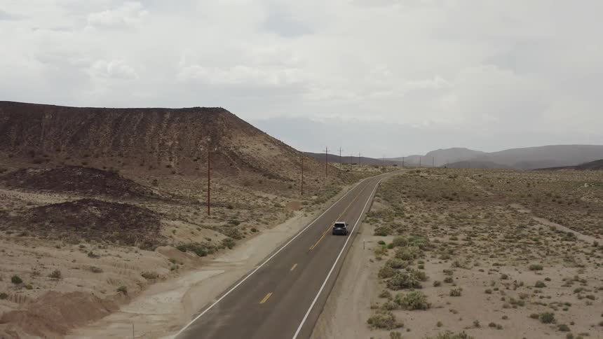 A lone car drives down the long stretch of road
