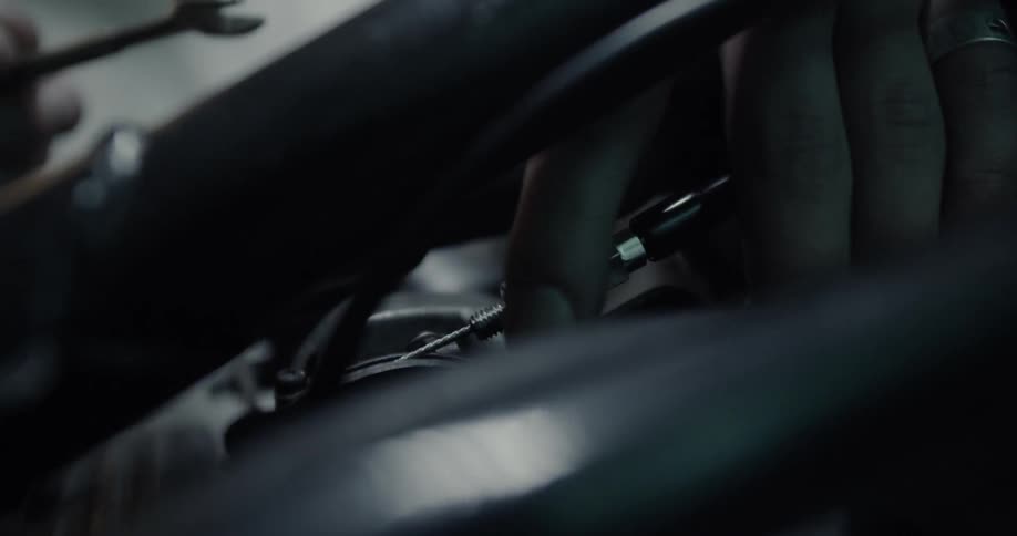 A man is working on a motorcycle inside a garage at night
