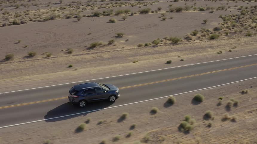 A car drives on a rural desert road