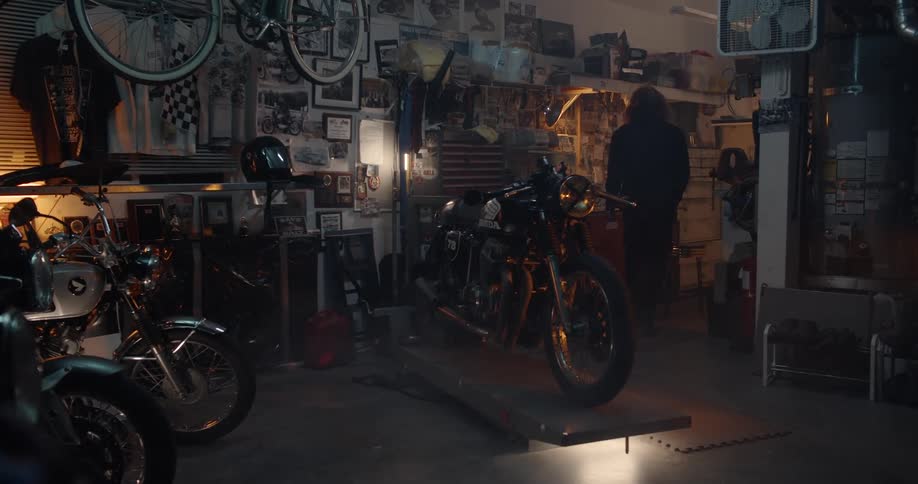 A man walks and sits at his workbench