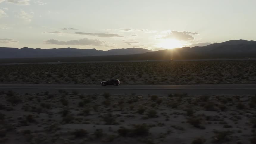 A car drives on a rural road at sunset