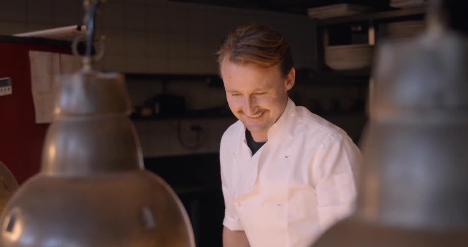Male cook in restaurant is talking and smiling in kitchen
