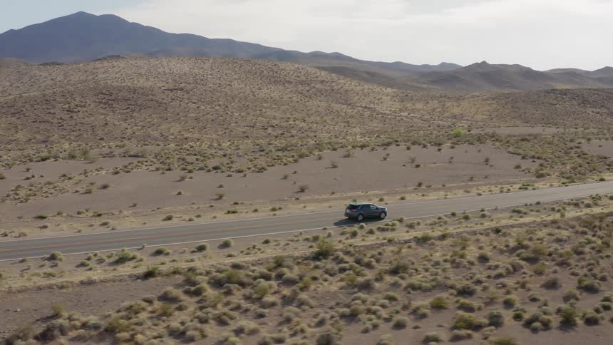 A car drives on a rural desert road