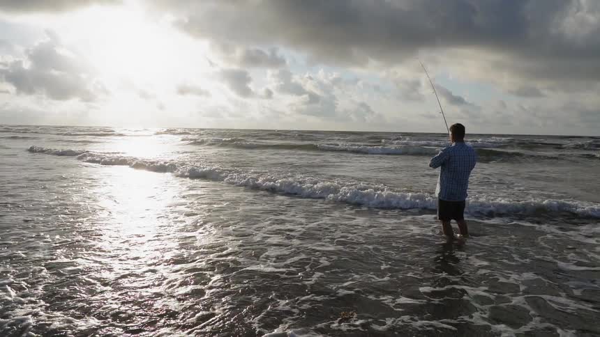 A man is fishing at sunrise at the beach