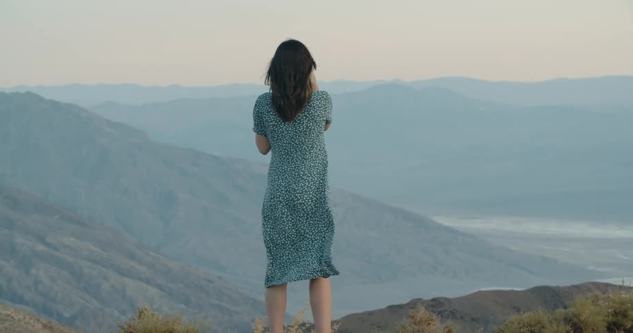 A woman takes a picture in mountains at sunset