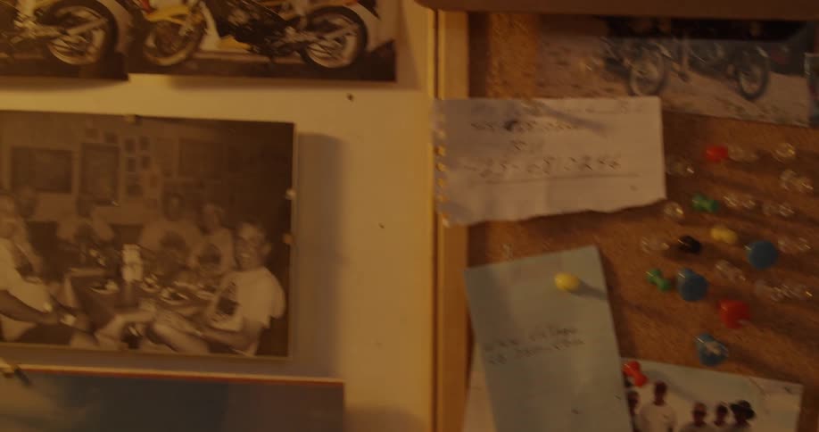 Photographs and a cork board hang on a wall