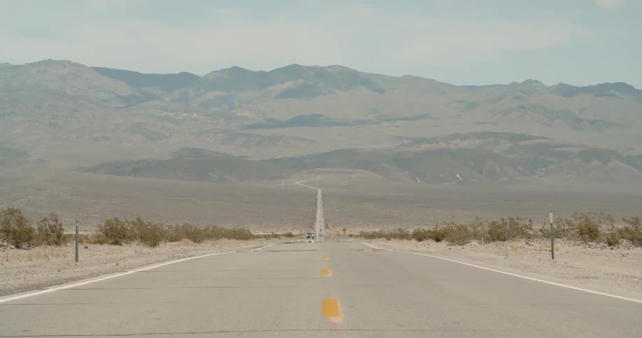 Empty highway with orange stripes sits near the mountains