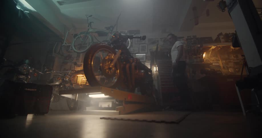 A man is standing by his motorcycle in the garage