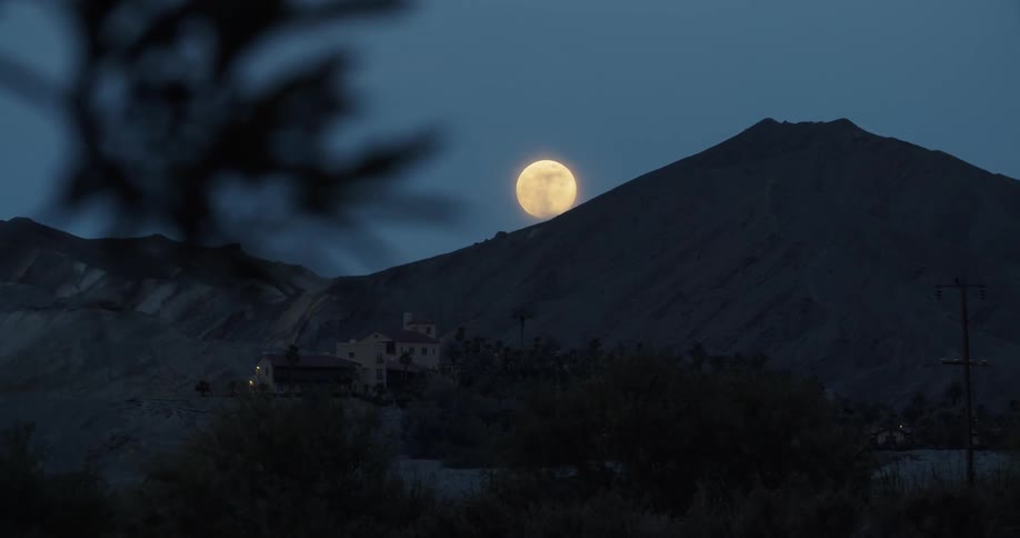 The moon glows above a mountain