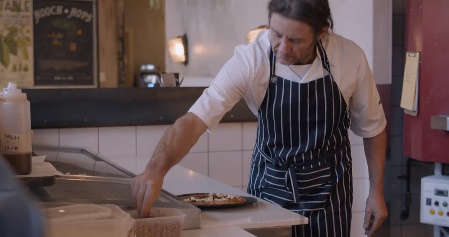 A man sprinkles spices on a dish