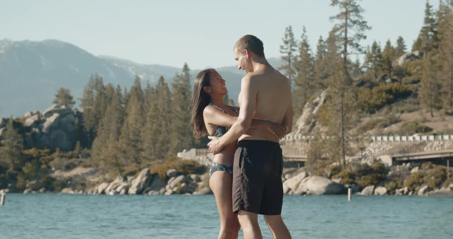 Man and woman hug next to a large body of water