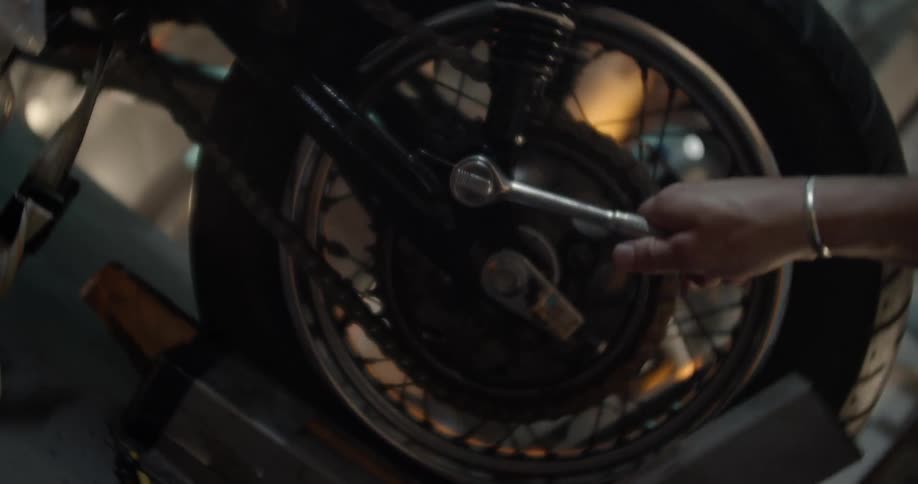 A man uses a tool on a motorcycle tire