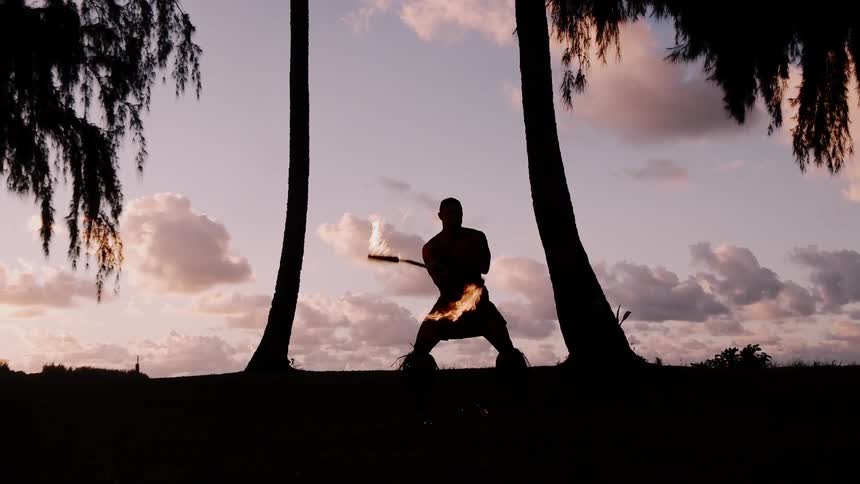 Fire dancer performing at sunset on the beach
