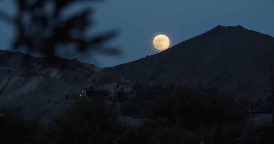 The moon glows above a mountain