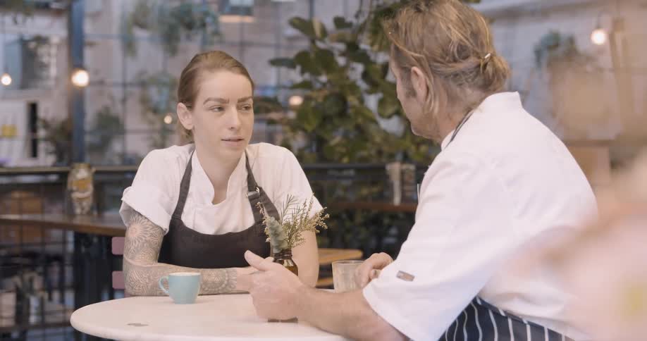 Two chefs sit at the table talking