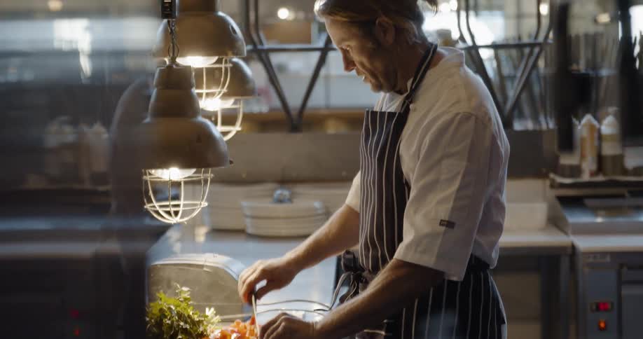 A chef cuts vegetables in a restaurant kitchen