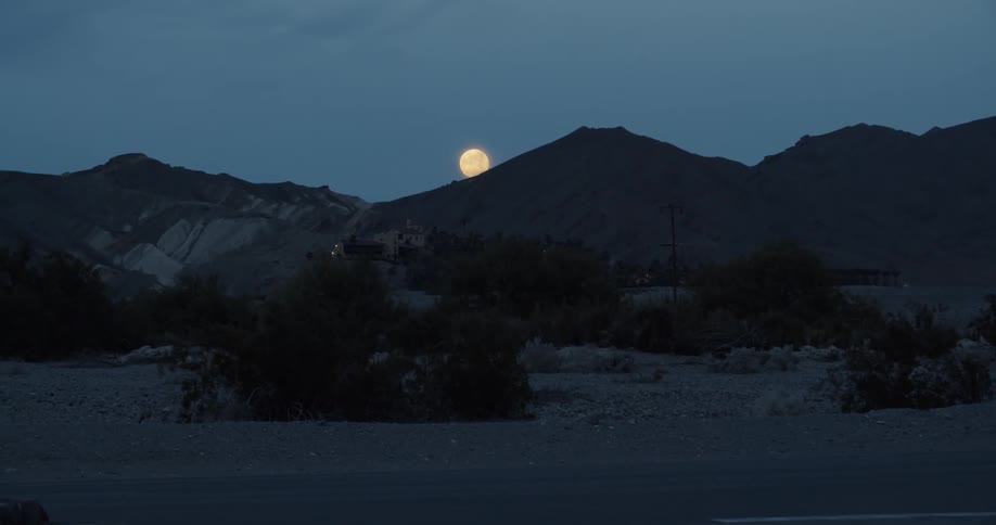 Moon rises over hills in a cloudy evening