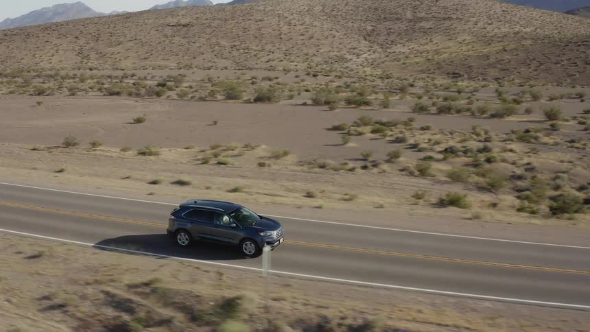 A car drives on a rural desert road