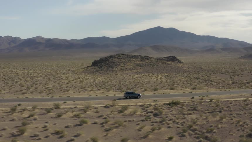 Car traveling on desolate mountain highway on cloudy day