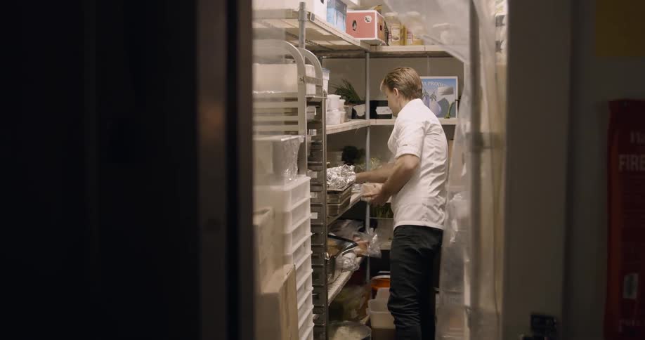 A chef gets ingredients from a storage room