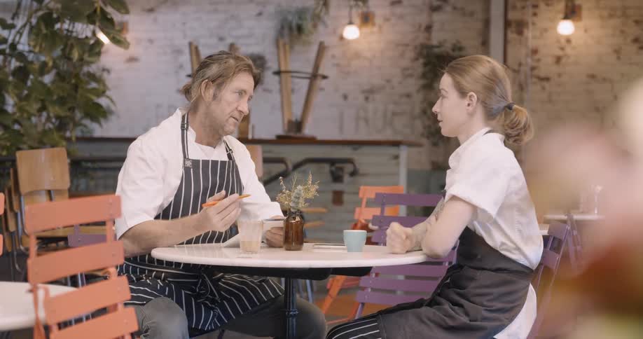 Two chefs talk in a restaurant dining room