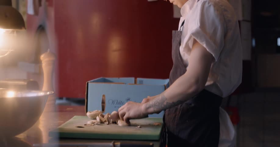 Woman chops mushrooms on a cutting board in a restaurant