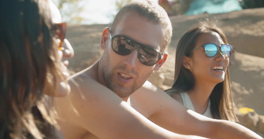 A man and two women talk on the beach