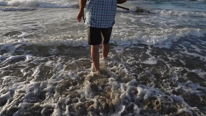 A person stands in the surf fishing