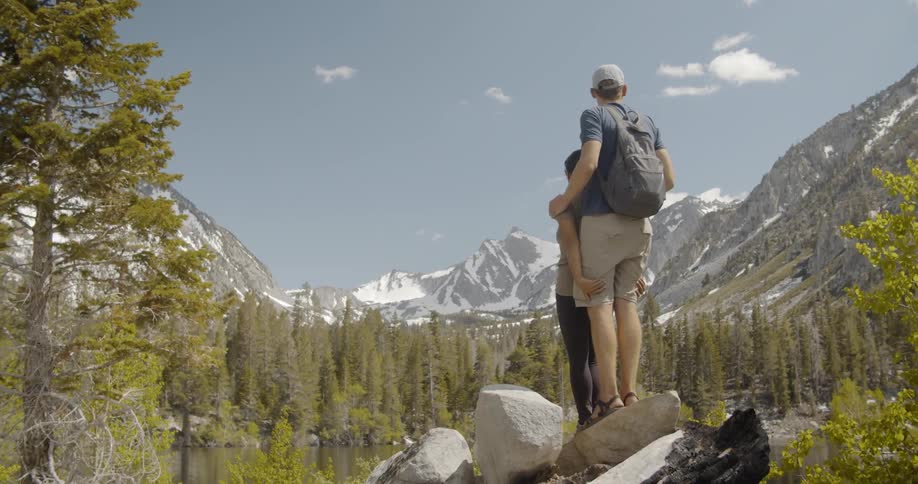 A couple stand on the rocks looking over the mountain
